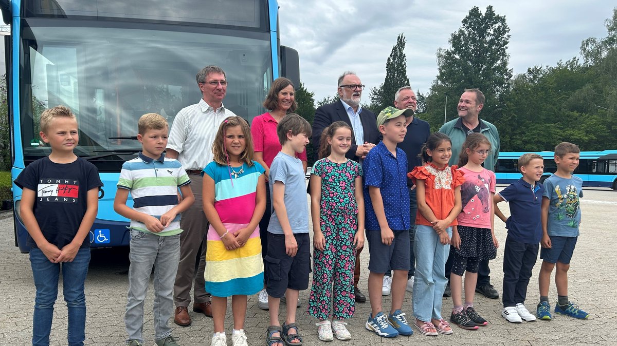 Zehn Kinder und fünf Erwachsene stehen auf einem Gruppenbild vor einem Bus in Passau.
