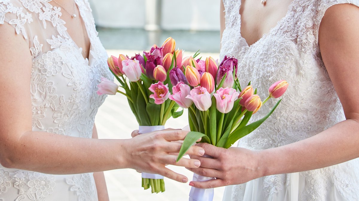 Zwei Frauen im Brautkleid und mit Hochzeitsstrauß bei ihrer Hochzeit. 