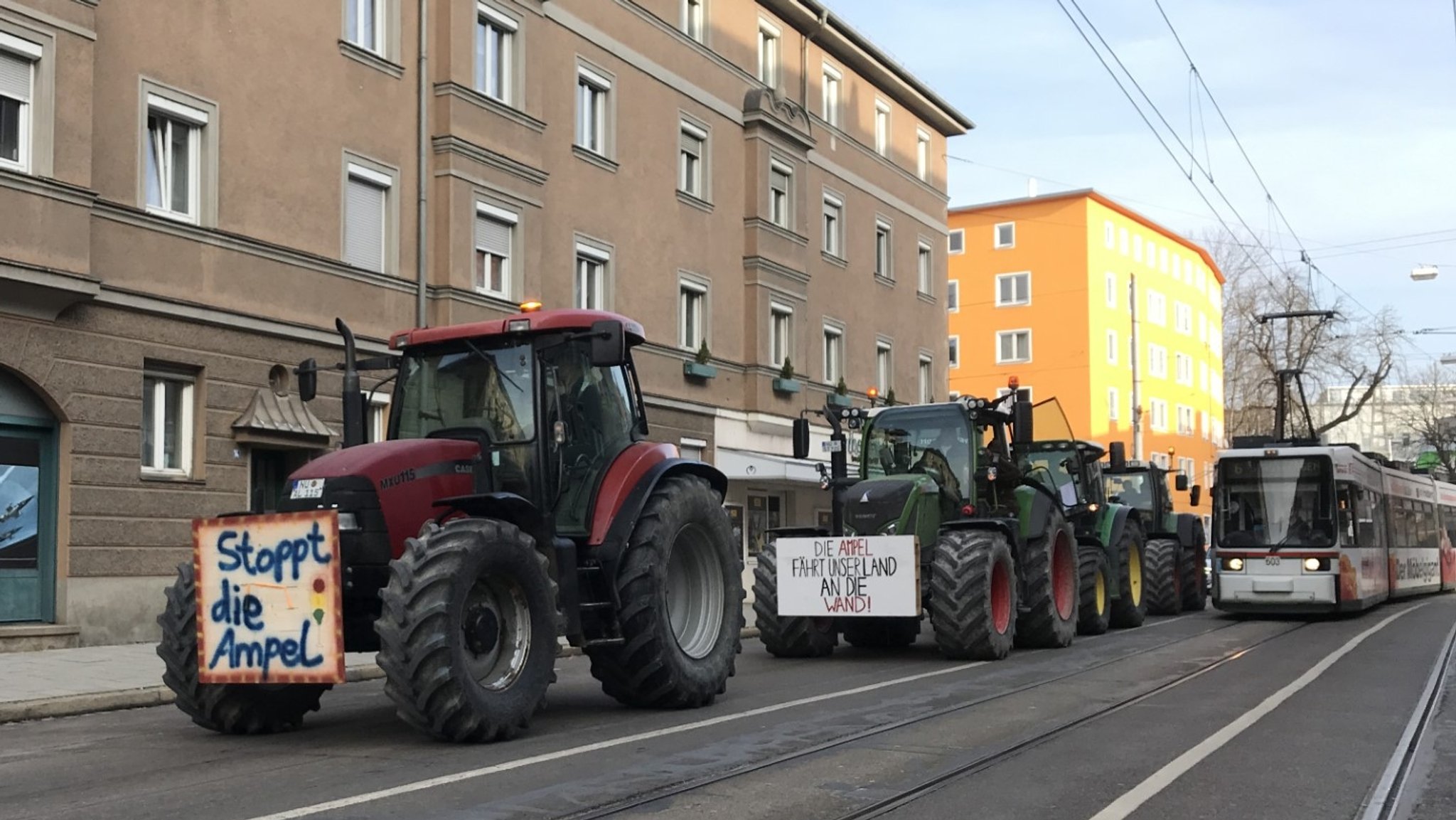 Mehrere Traktoren in der Augsburger Innenstadt neben einer Straßenbahn.