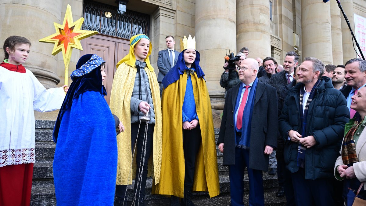 Michael Theurer (vorn 2.v.r), Landesvorsitzender der FDP Baden-Württemberg, und Christian Lindnder (r), Bundesvorsitzender der FDP und Bundesfinanzminister, stehen vor dem Opernhaus beim traditionellen Dreikönigstreffen der FDP zusammen mit einer Gruppe Sternsinger.