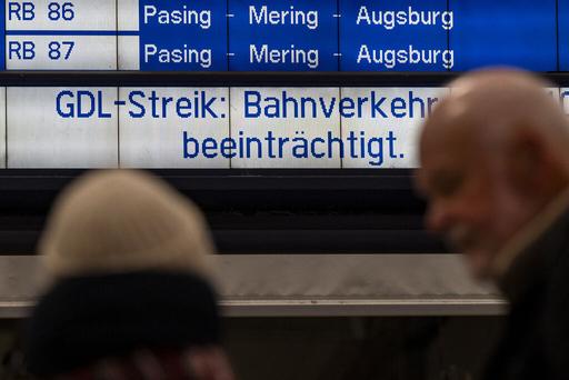 Bahnreisende stehen am Hauptbahnhof in München vor einer Anzeigetafel mit der Aufschrift "GDL-Streik: Bahnverkehr beeinträchtigt""
