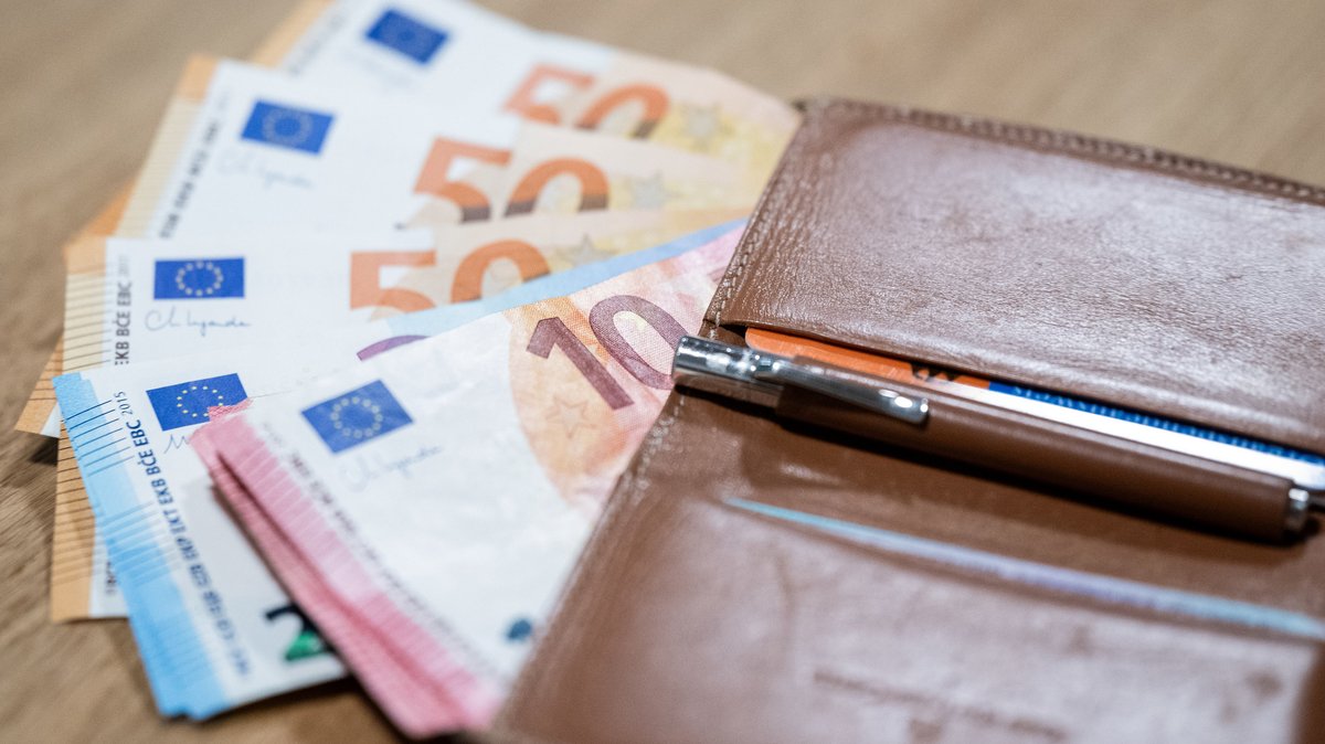 Euro-Banknoten und eine Geldbörse liegen auf einem Tisch.