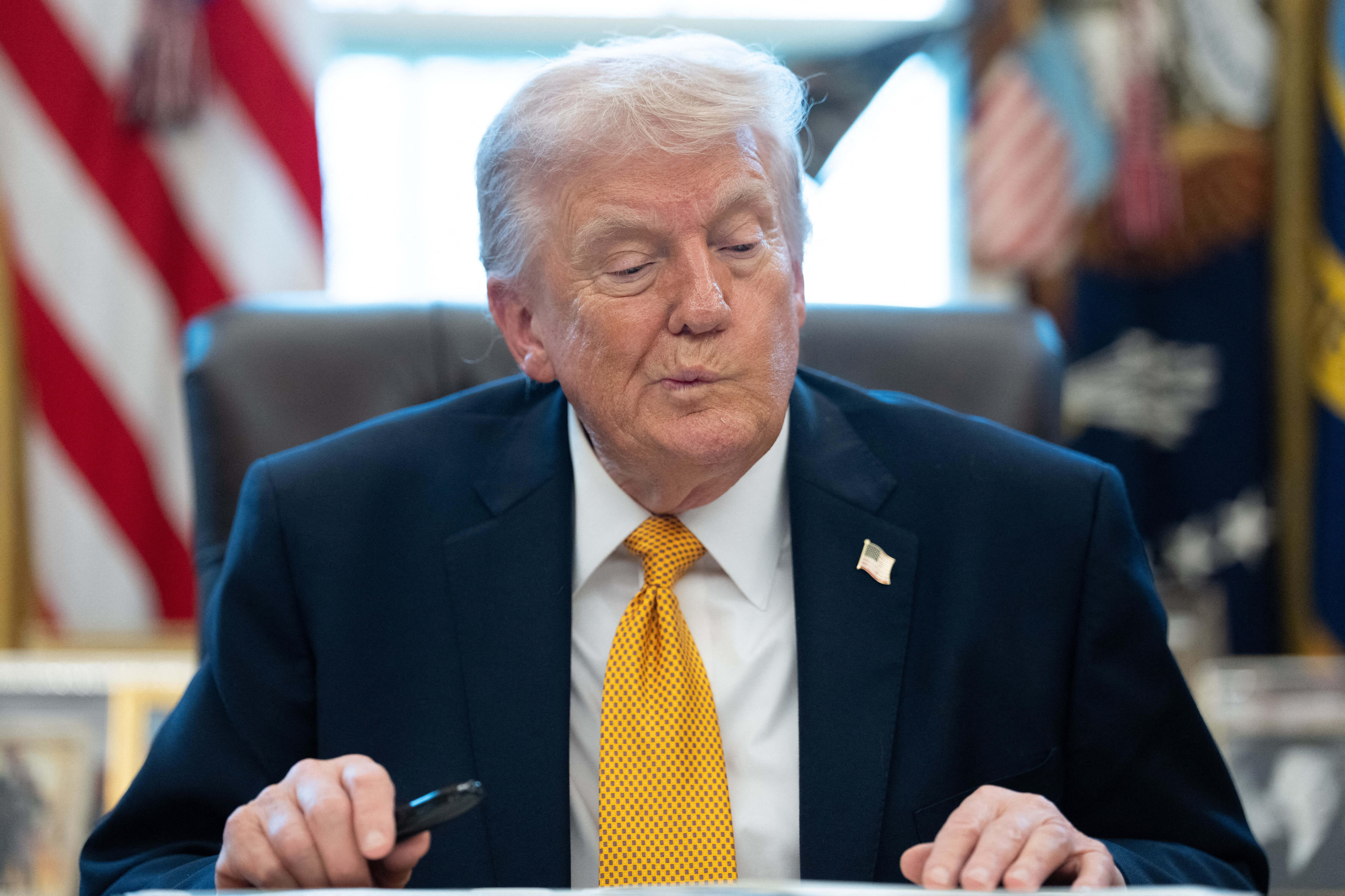 Archivbild: Der US-Präsident Donald Trump mit haderndem Gesichtsausdruck, während er im Oval Office im Weißen Haus etwas unterschreibt.