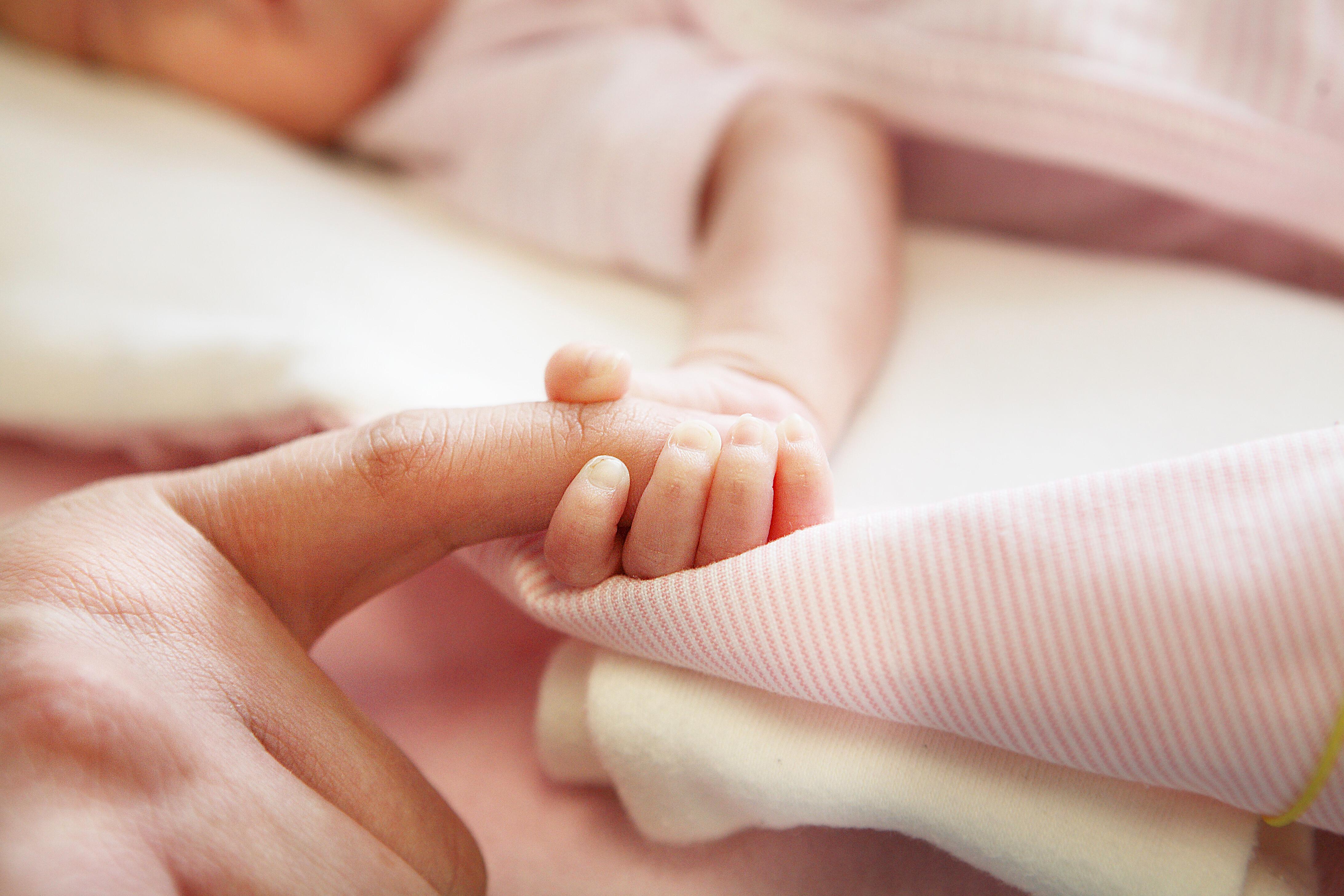 Neugeborenes Baby, dessen Hand gehalten wird