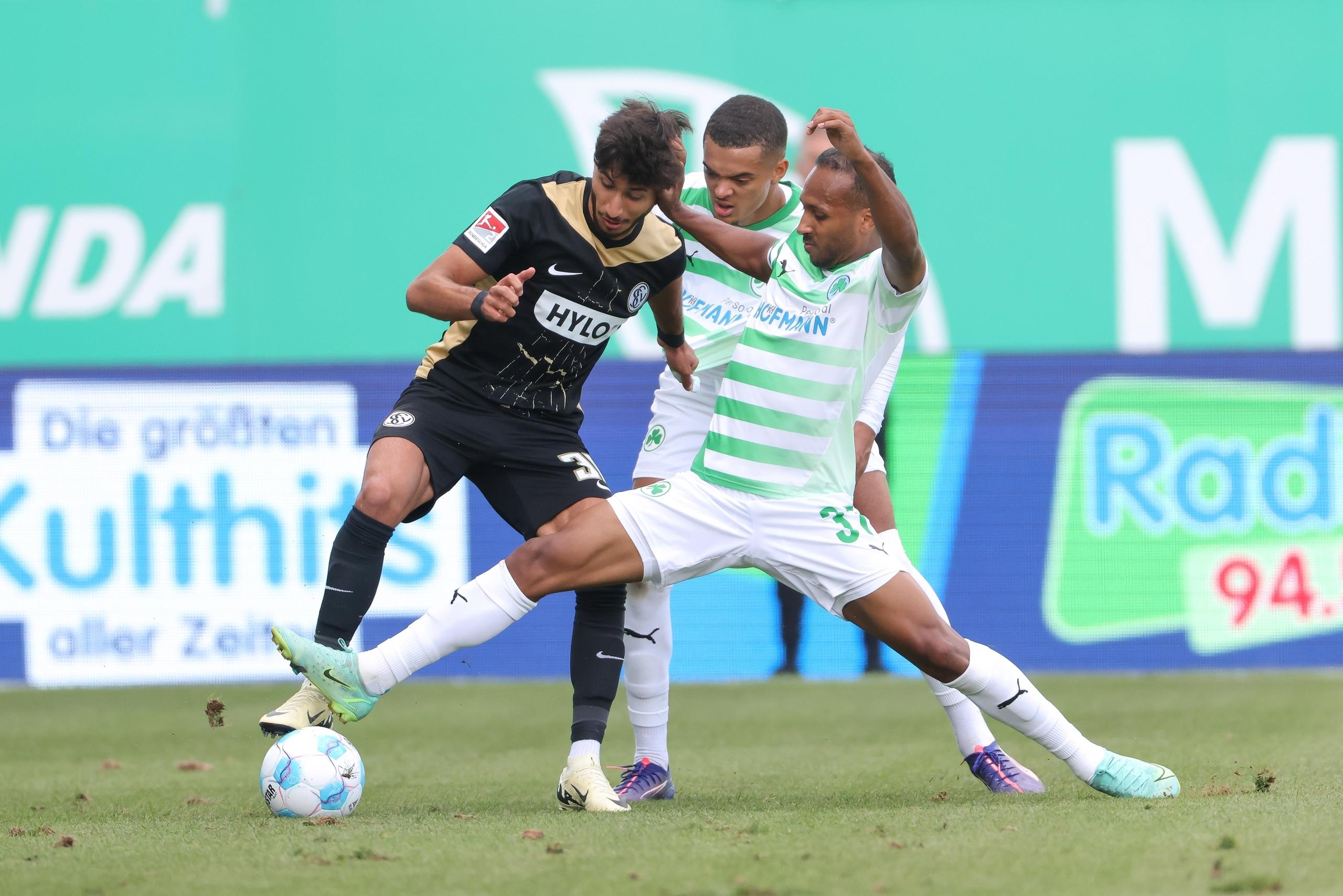 Julian Green (r) von Greuther Fürth attackiert Muhammed Mehmet Damar (l) vom SV Elversberg.