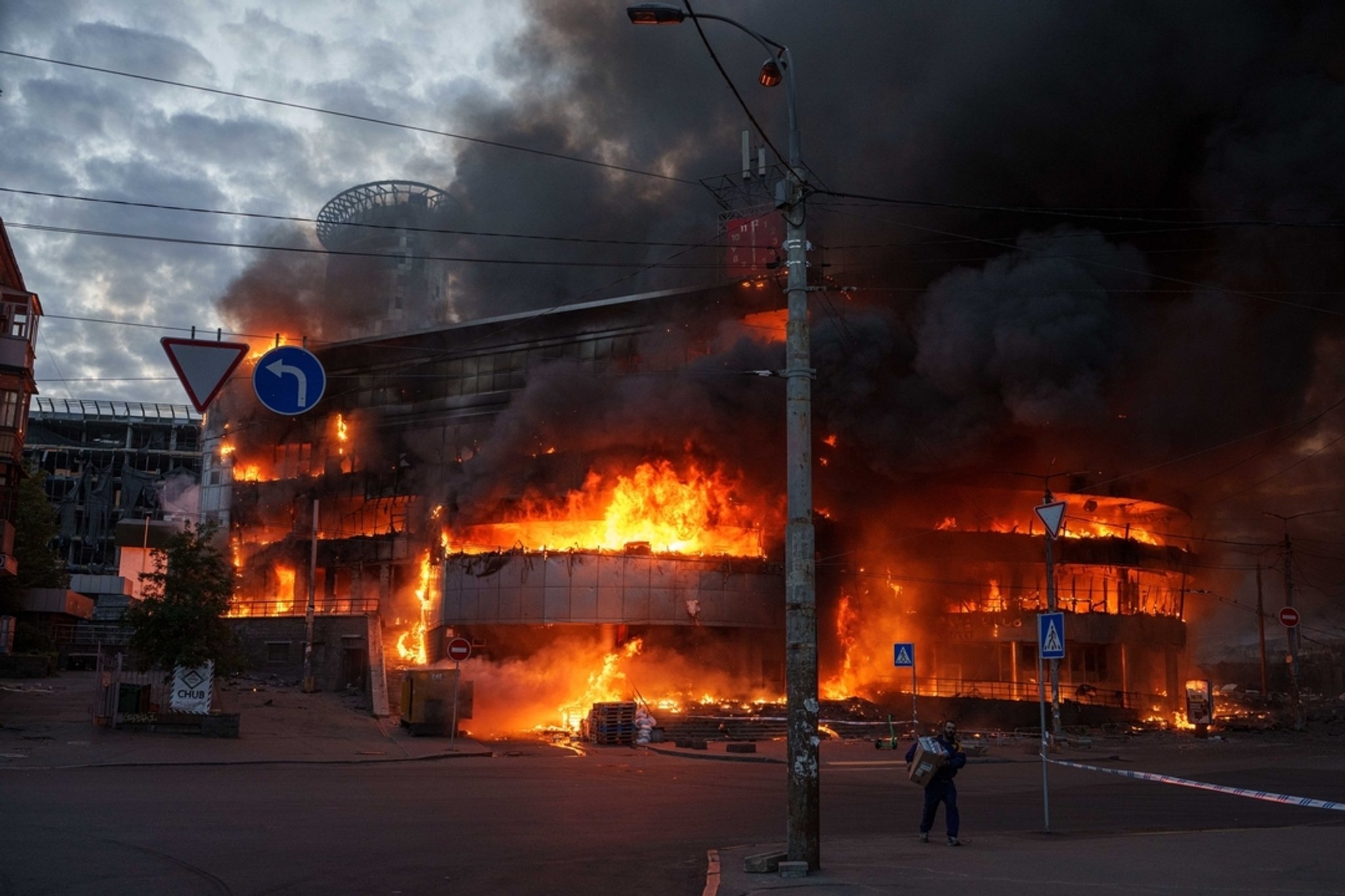 24.05.2026, Ukraine, Kiew: Ein Mann trägt eine Kiste aus einem brennenden Handelszentrum nach einem der schwersten russischen Angriffe auf Kiew. | Bild: dpa-Bildfunk/Evgeniy Maloletka 24.05.2026, Ukraine, Kiew: Ein Mann trägt eine Kiste aus einem brennenden Handelszentrum nach einem der schwersten russischen Angriffe auf Kiew.