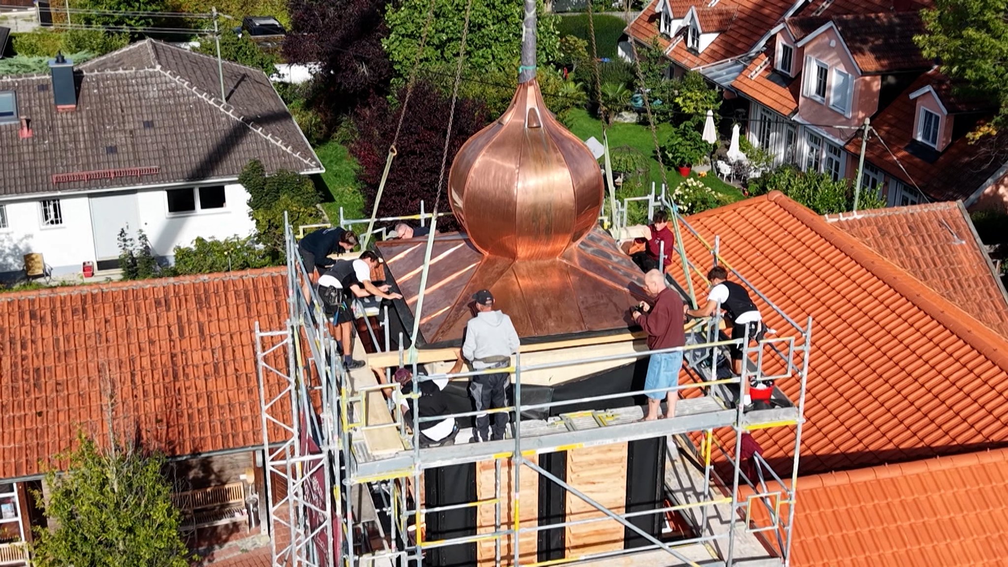 Die neue Zwiebelspitze wird von einem Kran auf den Turm der Christuskirche in Utting gesetzt.