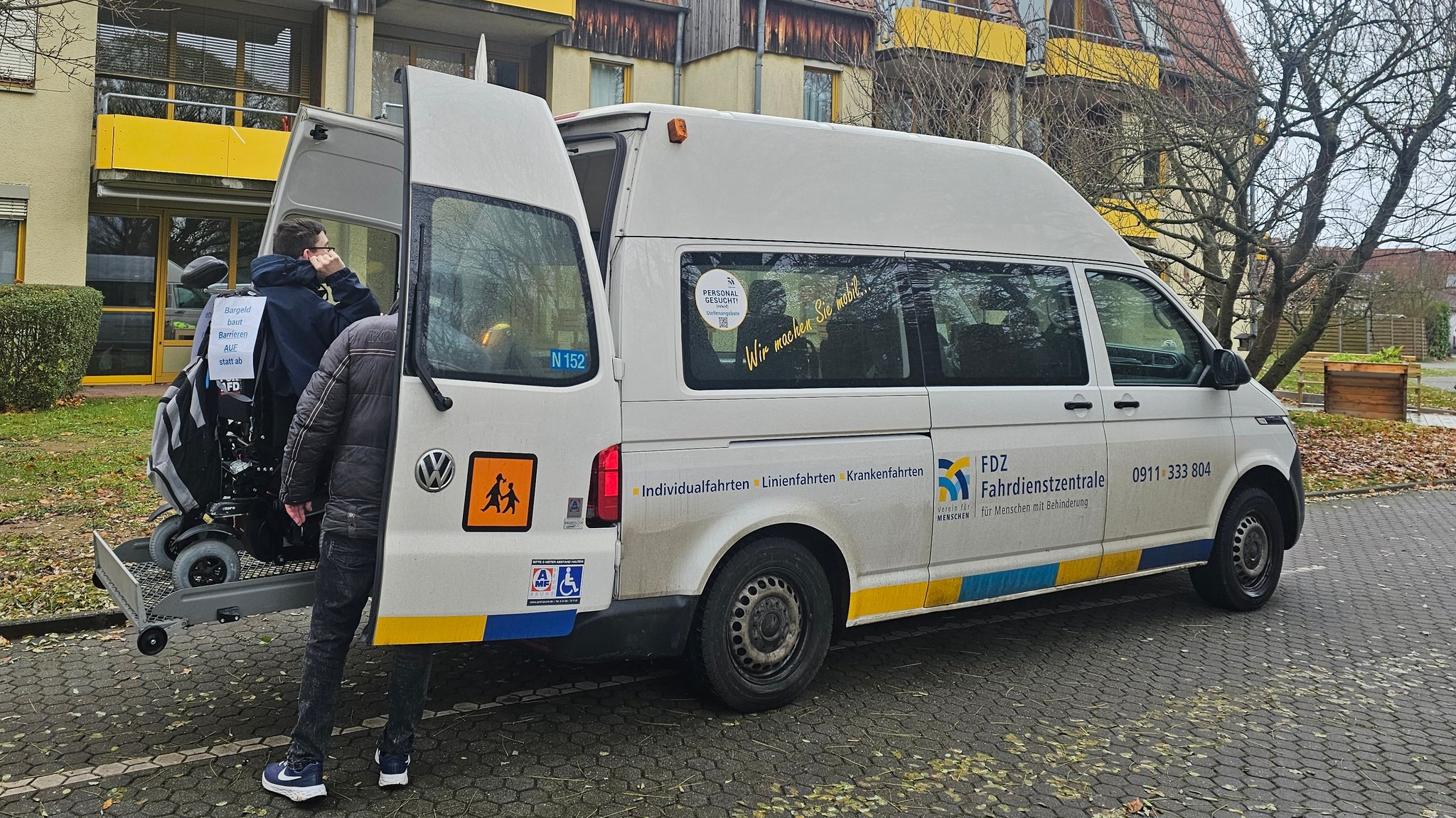 Ein Rollstuhlfahrer wir in einen Transporter verladen. 