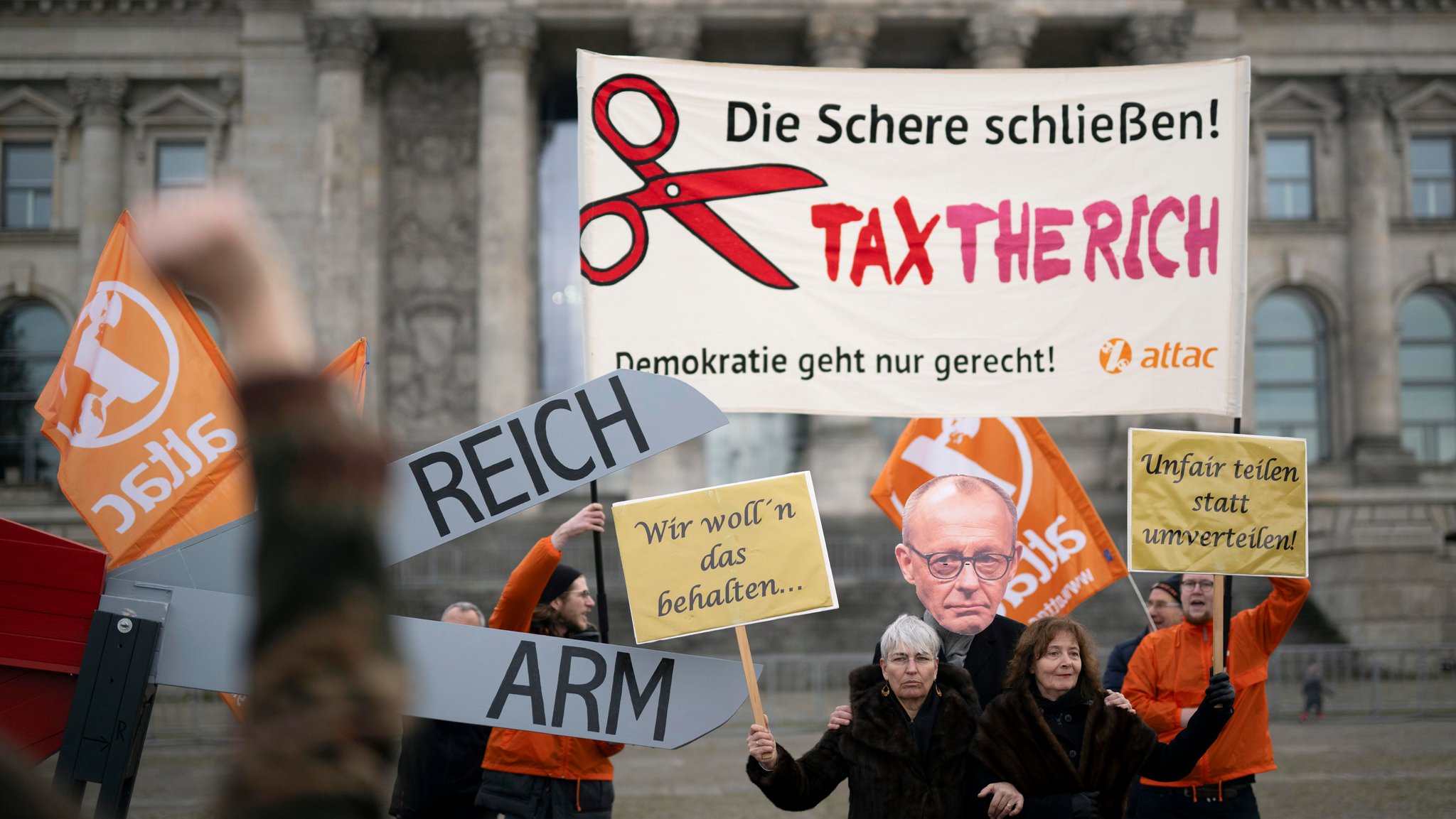 Aktivisten von Attac mit Schere Reich Arm und Maske "Friedrich Merz" sowiedem Transparent "Tax The Rich". | Bild: pa/dpa/Ipon | Stefan Boness Aktivisten von Attac mit Schere Reich Arm und Maske "Friedrich Merz" sowiedem Transparent "Tax The Rich".