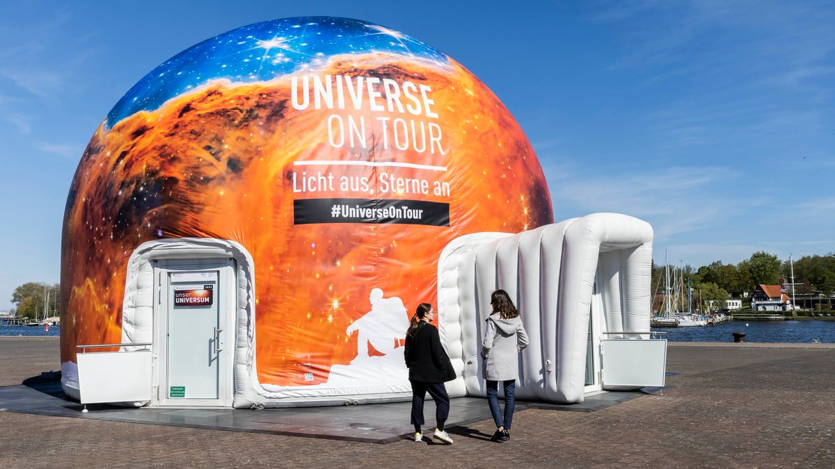 Zwei Frauen stehen vor einem mobilen Planetarium.   