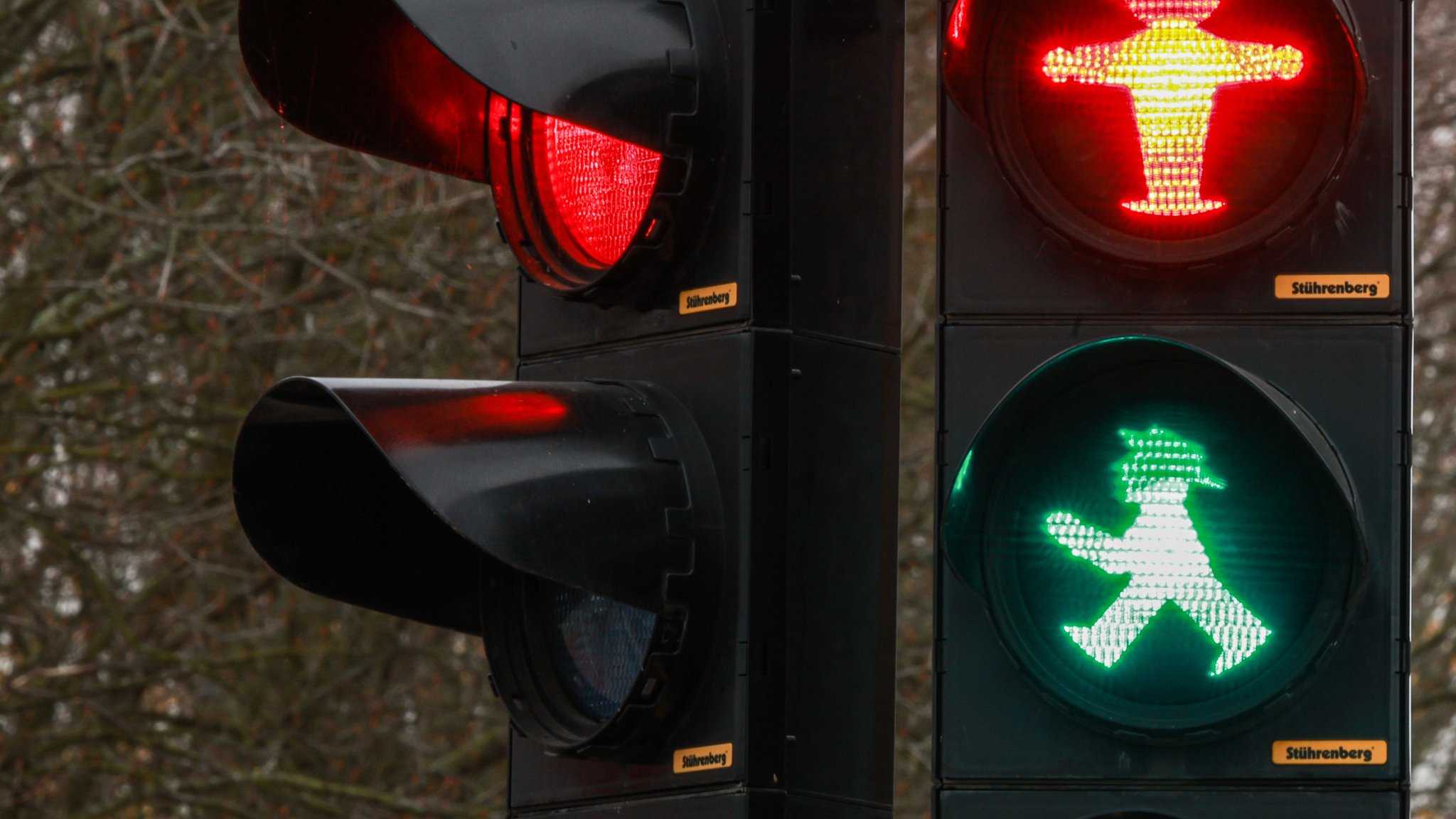 Eine Verkehrsampel, bei der das grüne Männchen und das rote leuchten.