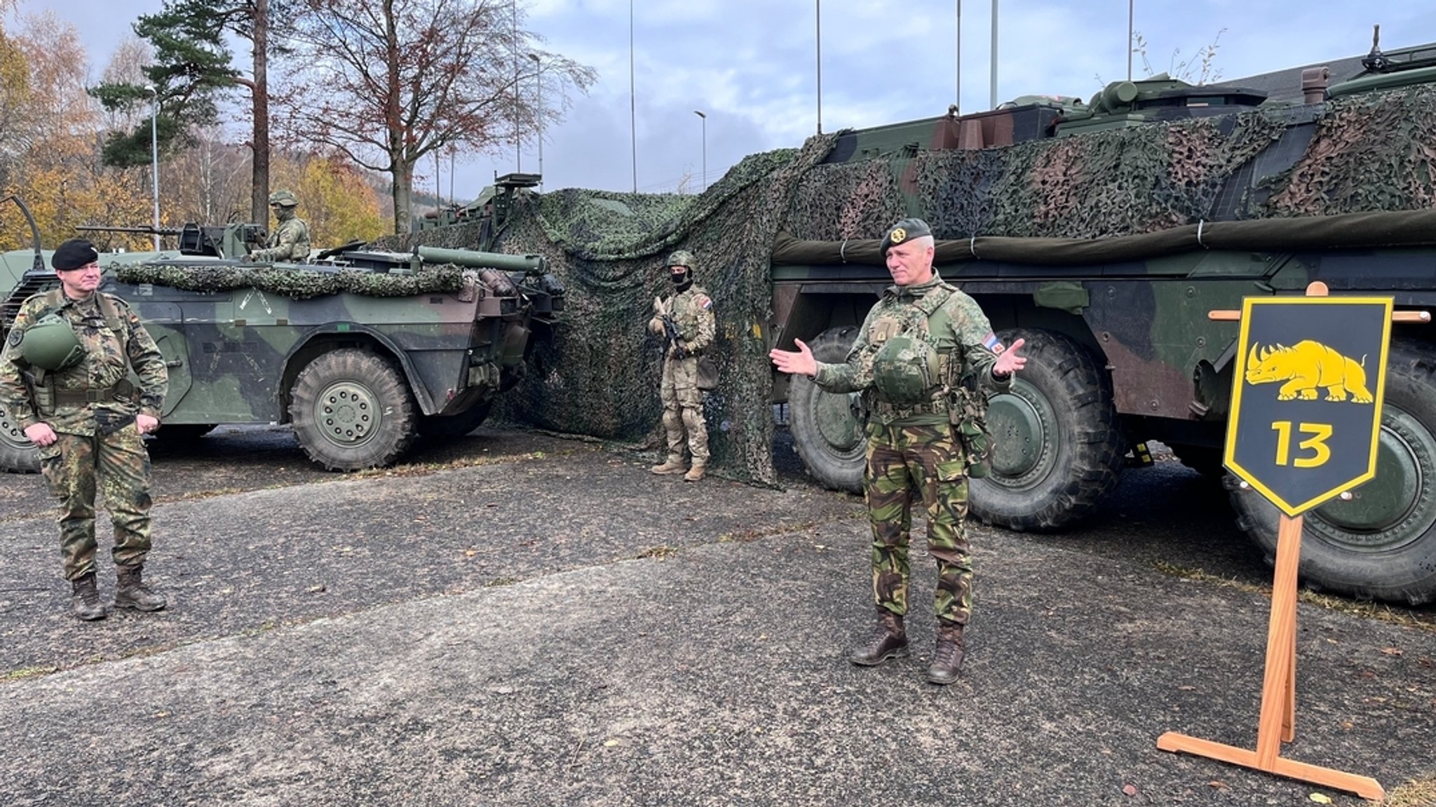 Männer in Tarnkleidung stehen vor getarnten Panzerfahrzeugen