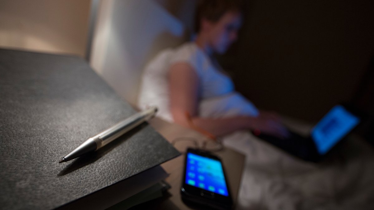 Junge Frau arbeitet nachts im Bett mit ihrem Laptop.