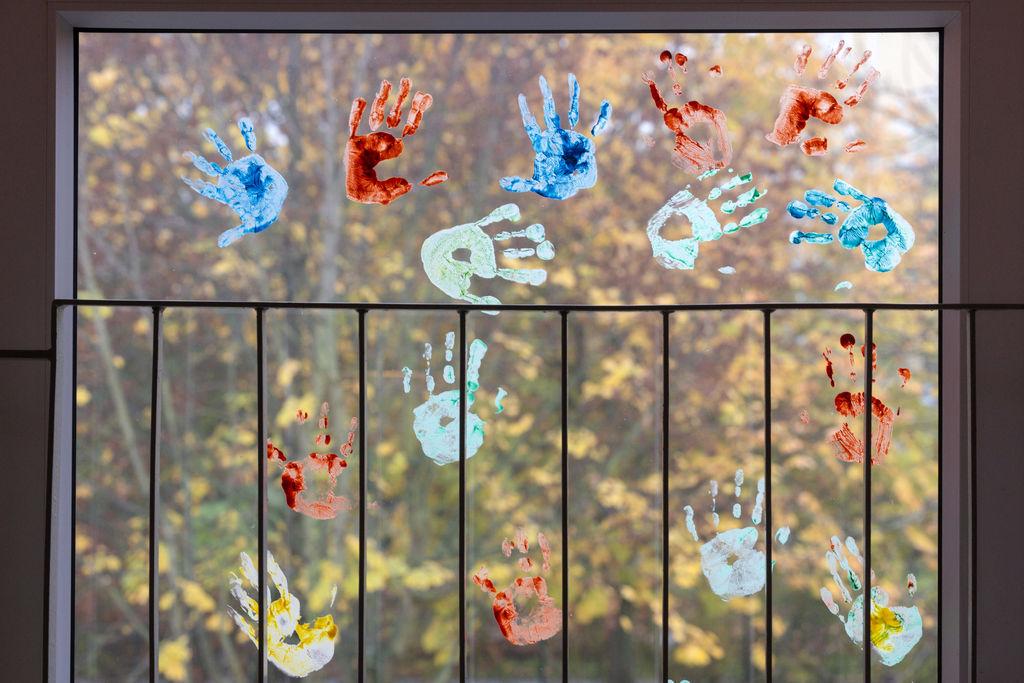 ARCHIV - 18.11.2022, Thüringen, Erfurt: Kinder haben in einem Kindergarten farbige Abdrücke ihrer Hände auf einem Fenster hinterlassen. 