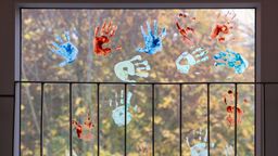 ARCHIV - 18.11.2022, Thüringen, Erfurt: Kinder haben in einem Kindergarten farbige Abdrücke ihrer Hände auf einem Fenster hinterlassen.  | Bild:dpa-Bildfunk/Michael Reichel