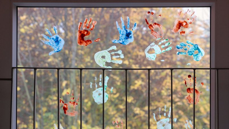 ARCHIV - 18.11.2022, Thüringen, Erfurt: Kinder haben in einem Kindergarten farbige Abdrücke ihrer Hände auf einem Fenster hinterlassen. 