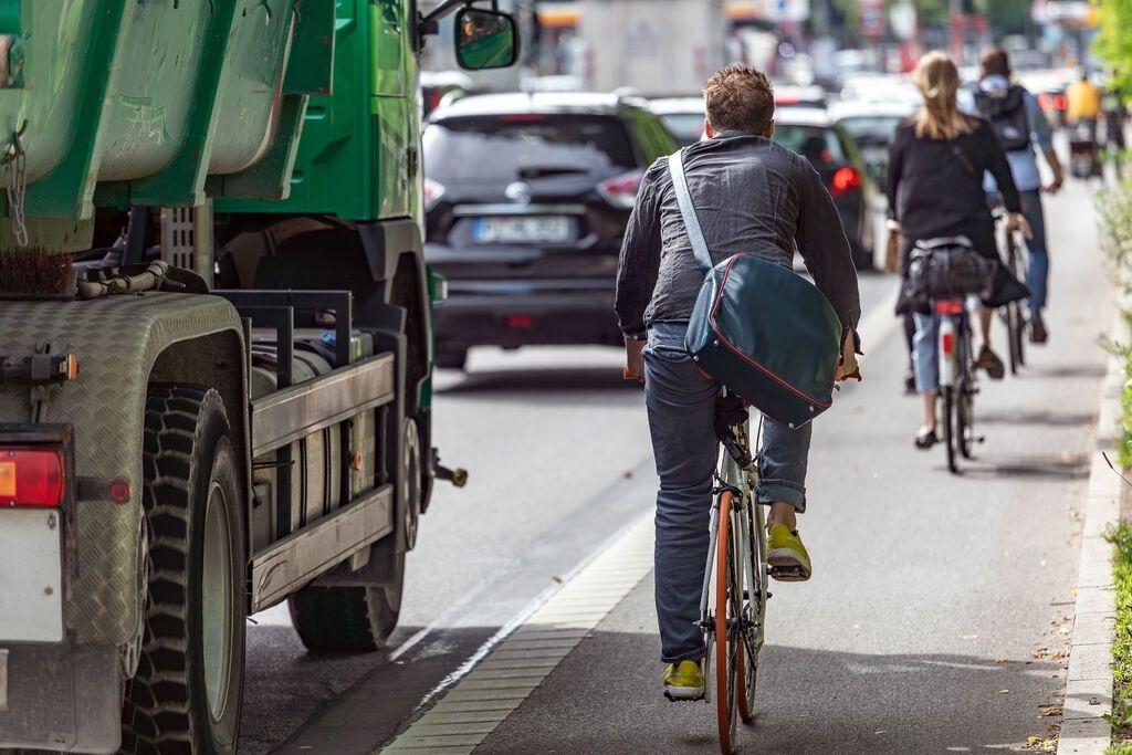 Mann fährt in der Stadt auf einem Fahrrad Weg neben der Straße.