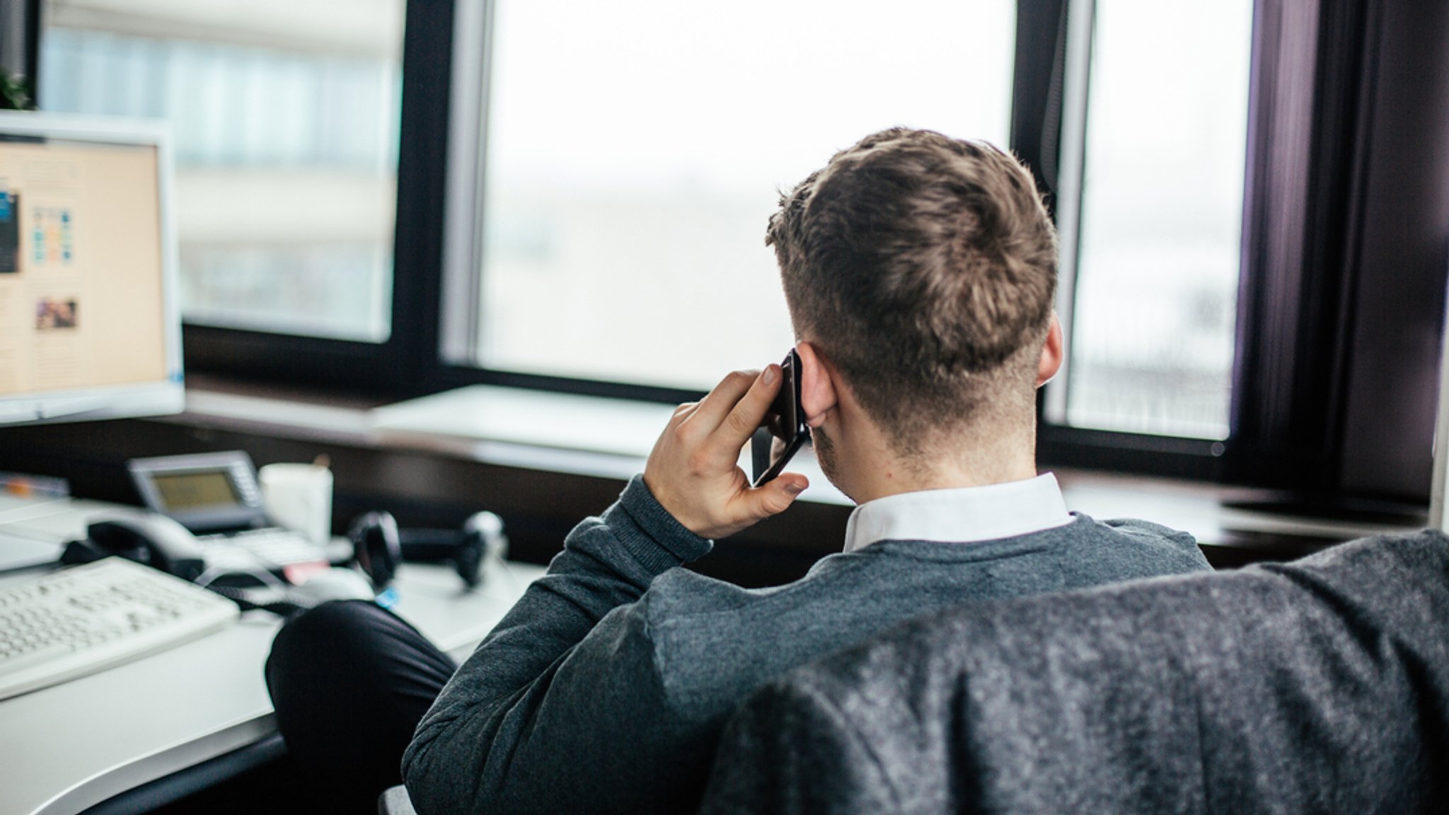 Ein Mitarbeiter telefoniert am Arbeitsplatz mit dem Handy.