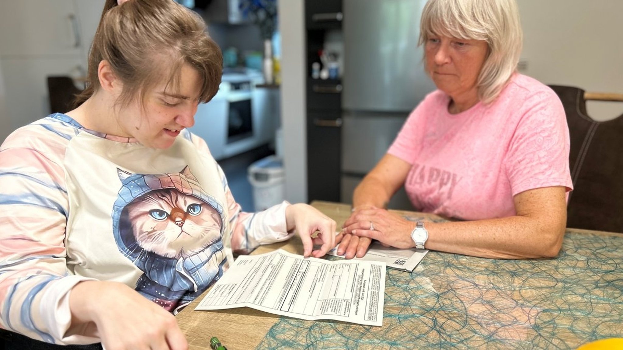 Zwei Frauen sitzen an einem Tisch. Vor ihnen liegt die Wahlbescheinigung zur Europawahl 2024. 