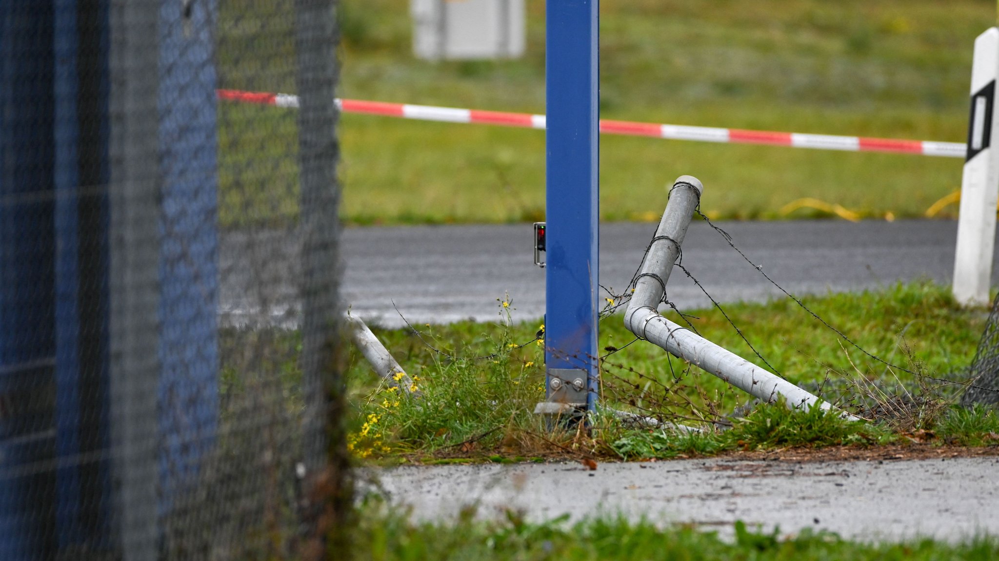 18.10.2026, Sachsen, Schkeuditz: Das durchbrochene Zaunelement an der Zufahrt zum Flugplatzgelände ist zu sehen. Die Polizei ermittelt nach einem erneuten Sicherheitsvorfall am Flughafen Leipzig/Halle an der Landebahn Nord. Foto: Heiko Rebsch/dpa +++ dpa-Bildfunk +++