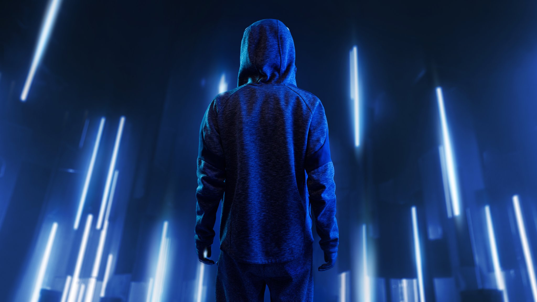 Eine Person in einem Kapuzenpullover steht vor einer Licht-Kulisse.