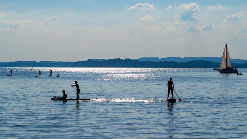 Symbolbild: Segelboot und Stand-up-Paddler am Chiemsee | Bild: stock.adobe.com/Lavizzara Symbolbild: Segelboot und Stand-up-Paddler am Chiemsee