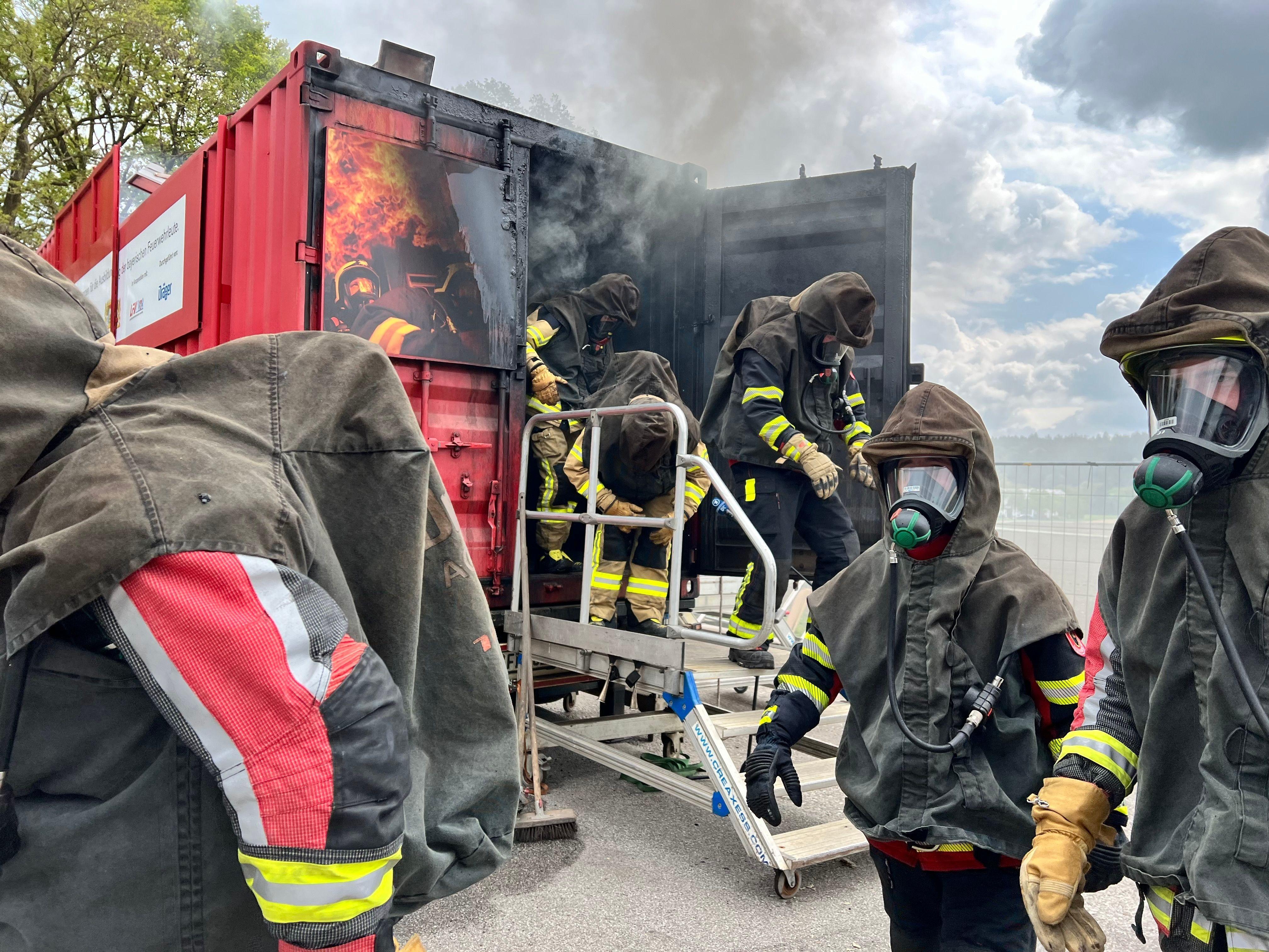 Feuerwehrkräfte kommen nach der Schulung aus dem Brandcontainer.