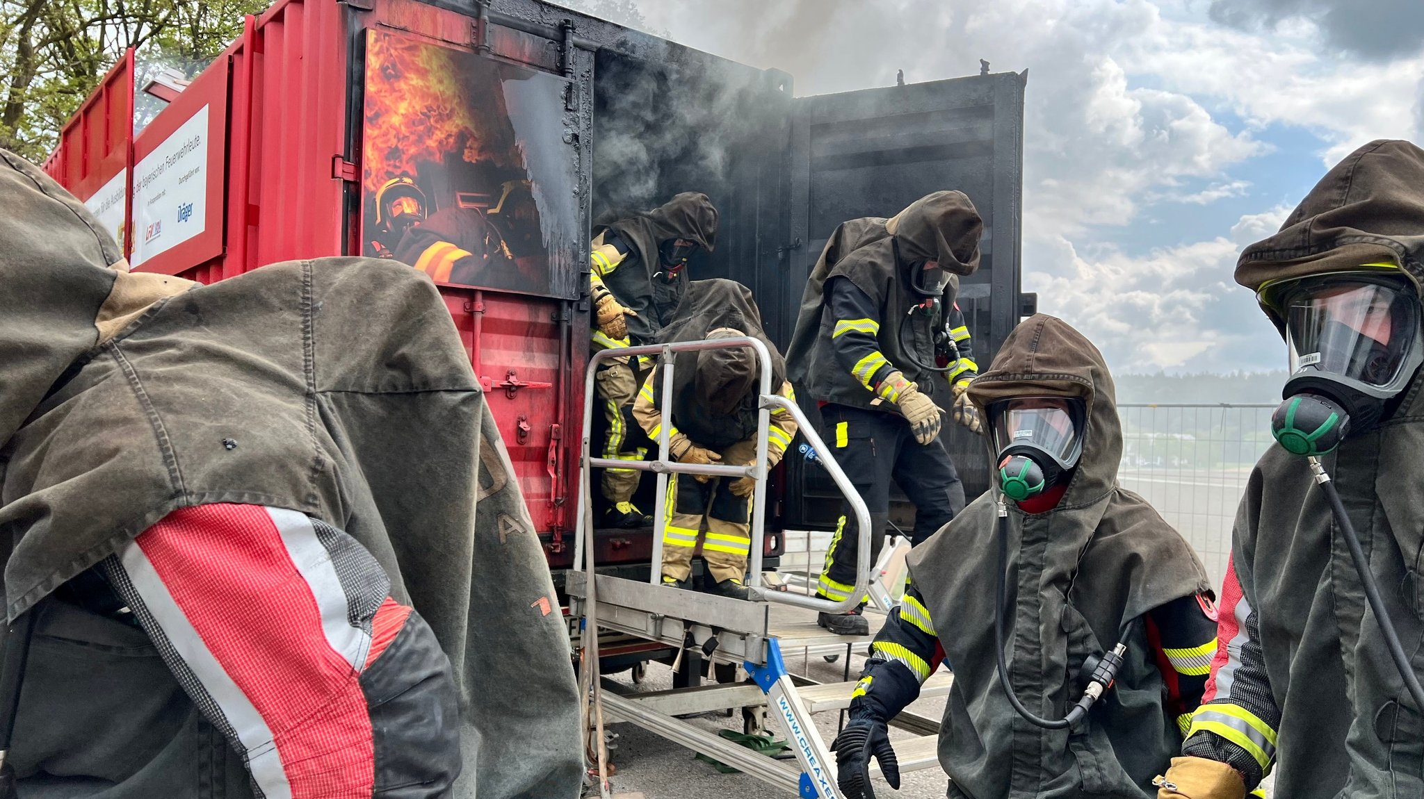 Feuerwehrkräfte kommen nach der Schulung aus dem Brandcontainer.