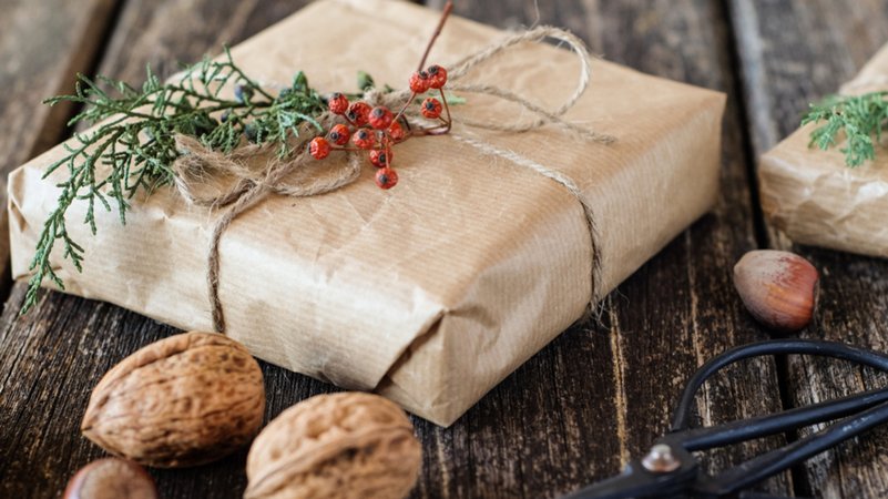 Weihnachtsgeschenk und Nüsse auf einem Holztisch (Symbolbild)