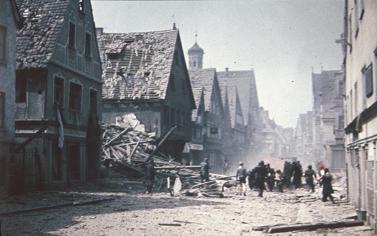 Die Kalchstraße in Memmingen kurz vor Kriegsende voller Schutt, viele Häuser sind stark beschädigt.