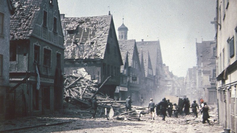 Die Kalchstraße in Memmingen kurz vor Kriegsende voller Schutt, viele Häuser sind stark beschädigt.