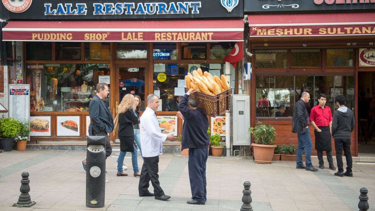 Ein Händler trägt einen Brotkorb vor einem Restaurant in einer Istanbuler Flanierstraße.