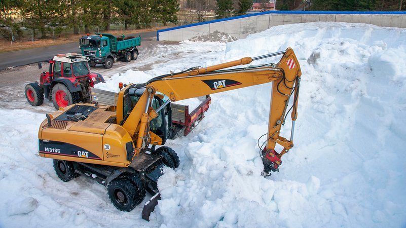 Baufahrzeuge baggern Schnee aus Depot
