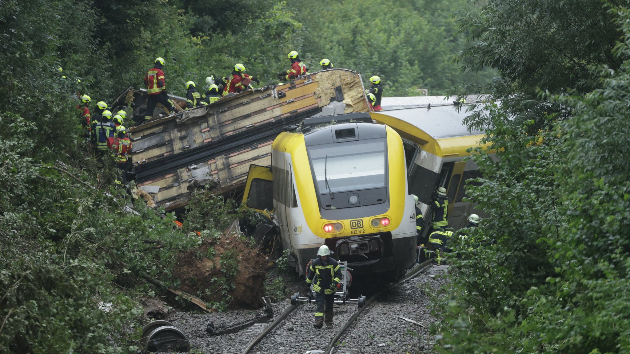 Einsatzkräfte arbeiten sich auf einem entgleisten und umgekippten Waggon zu den Fahrgästen vor.