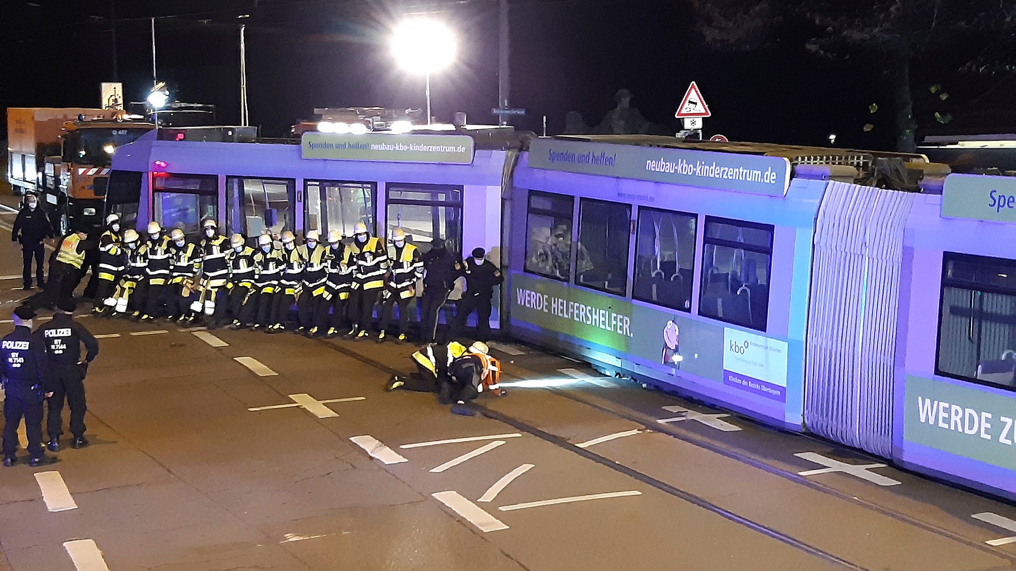 Mitarbeiter der Feuerwehr versuchen Straßenbahn wieder ins Gleis zu schieben