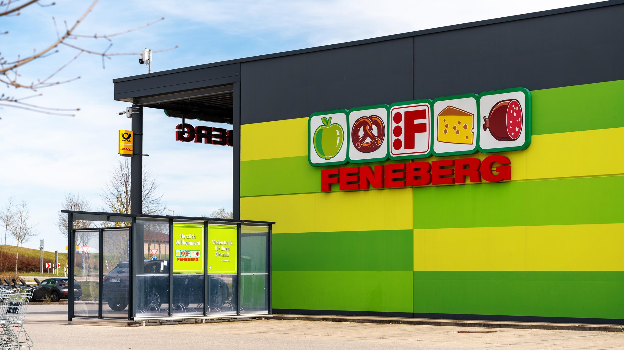 Eine Feneberg-Filiale mit Eingangsbereich, Einkaufswagen bzw. Einkaufswagen und Parkplatz zeigt den stationären Lebensmittelhandel im Allgäu.