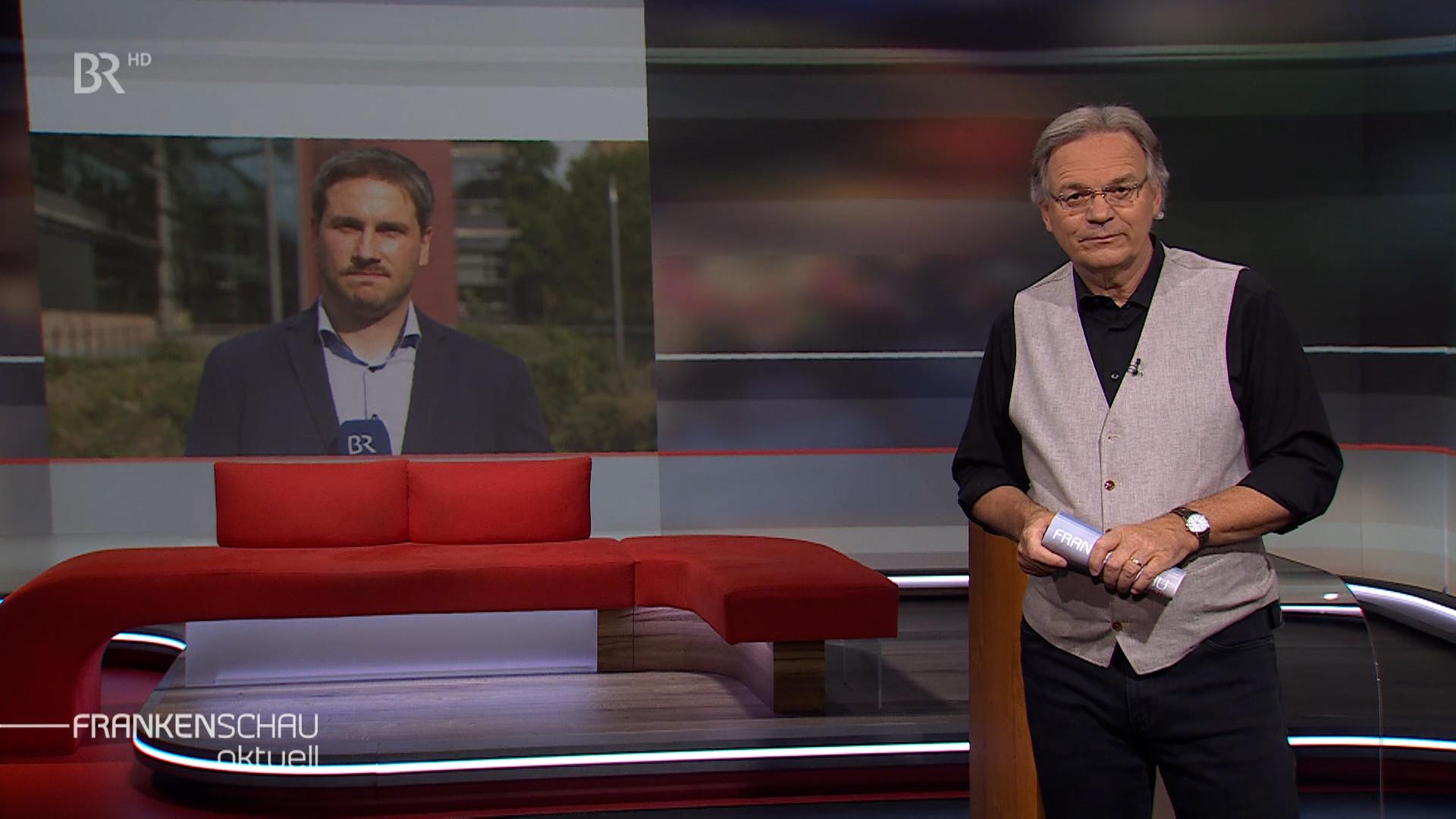 Moderator Charly Hilpert im Gespräch mit BR-Korrespondent Christoph Schneider in Würzburg.