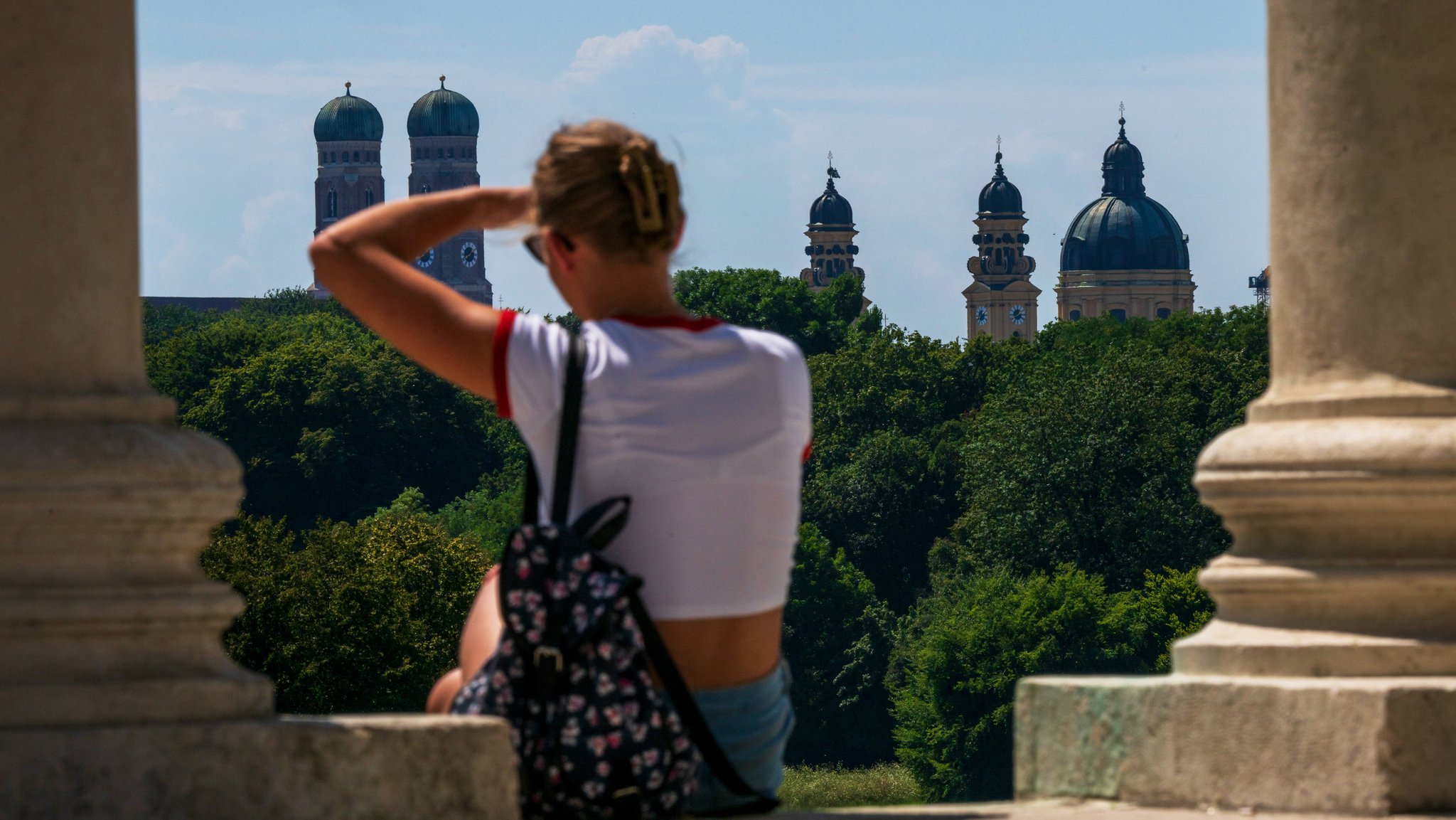 Eine Frau in München genießt vom Monopteros im Englischen Garten die Aussicht auf die bayerische Landeshauptstadt.