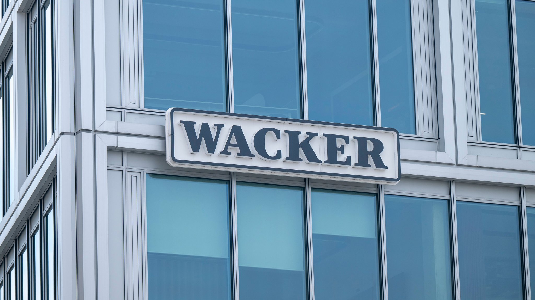 ARCHIV - 03.03.2026, Bayern, München: Das Unternehmenslogo (Firmenlogo) der Wacker Chemie AG auf einem Schild der Unternehmenszentrale «Wacker House» zu sehen. (zu dpa: «Keine Entlassungen bei Wacker nach Einigung auf Sparprogramm») Foto: Peter Kneffel/dpa +++ dpa-Bildfunk +++ | Bild: dpa-Bildfunk/Peter Kneffel ARCHIV - 03.03.2026, Bayern, München: Das Unternehmenslogo (Firmenlogo) der Wacker Chemie AG auf einem Schild der Unternehmenszentrale «Wacker House» zu sehen. (zu dpa: «Keine Entlassungen bei Wacker nach Einigung auf Sparprogramm») Foto: Peter Kneffel/dpa +++ dpa-Bildfunk +++