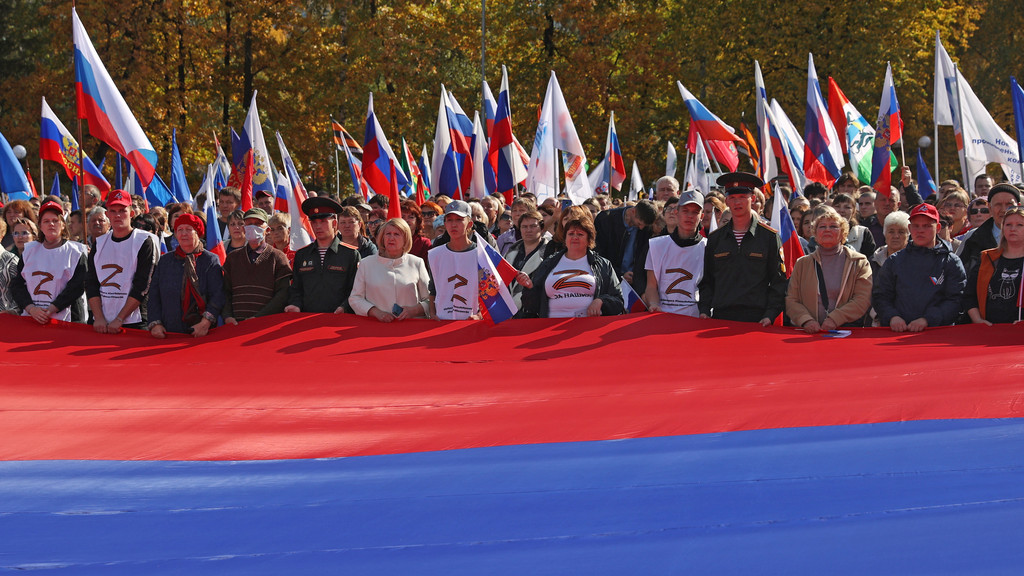 Demonstranten hinter riesengroßer russischer Flagge