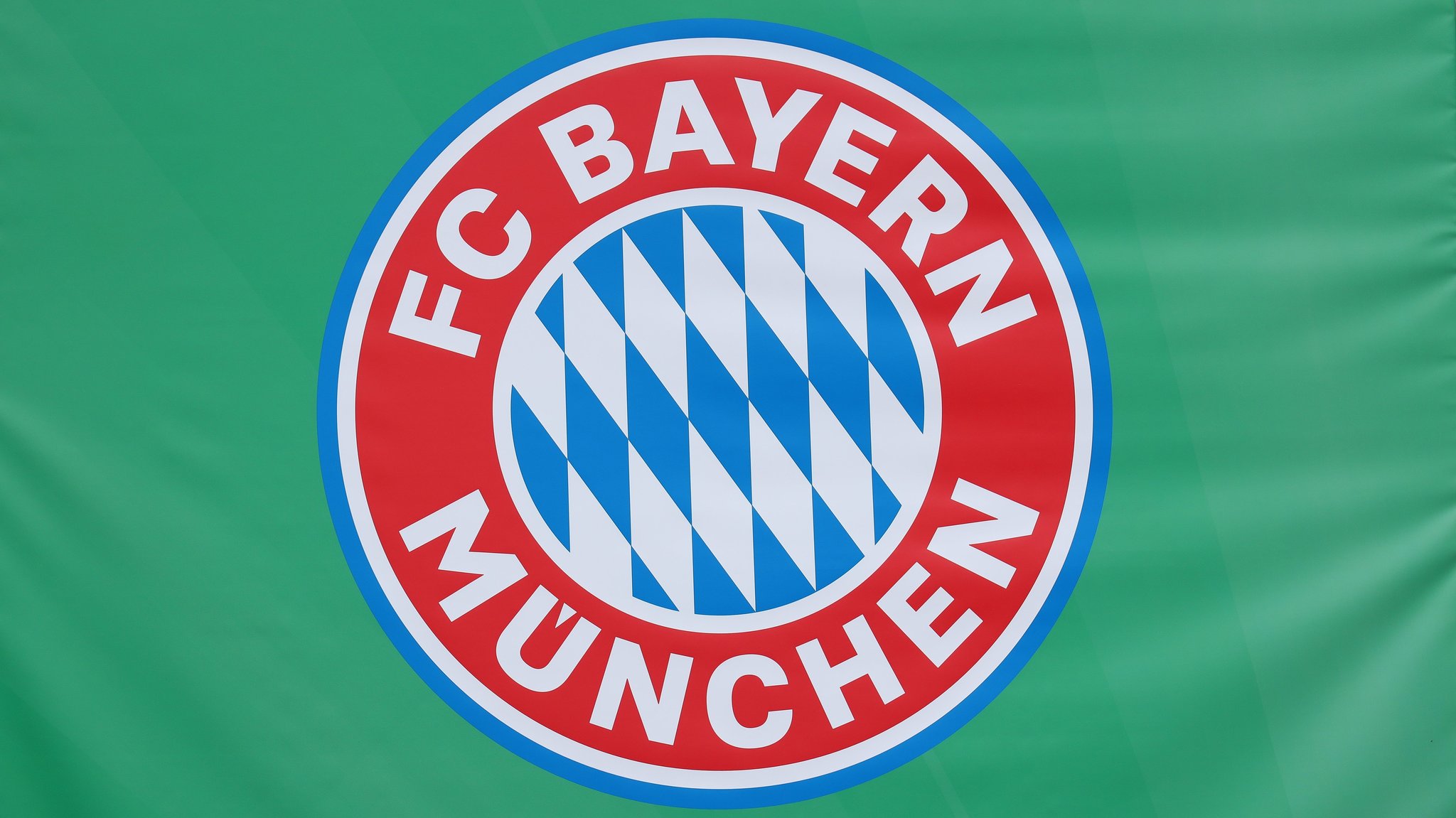 Logo des FC Bayern München auf grünem Hintergrund