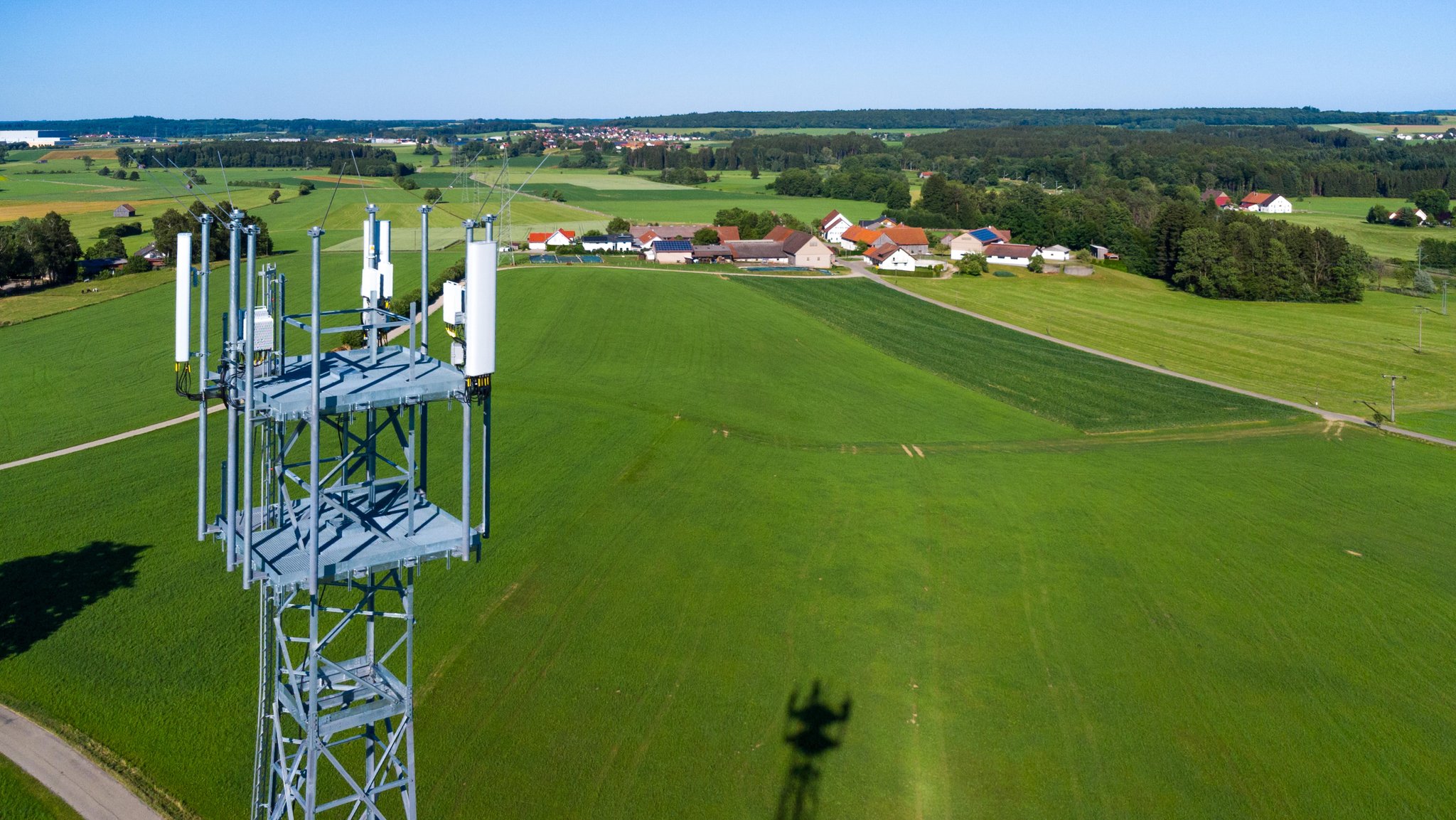 Mobilfunkmast auf dem Land. Im Hintergrund ein Dorf.