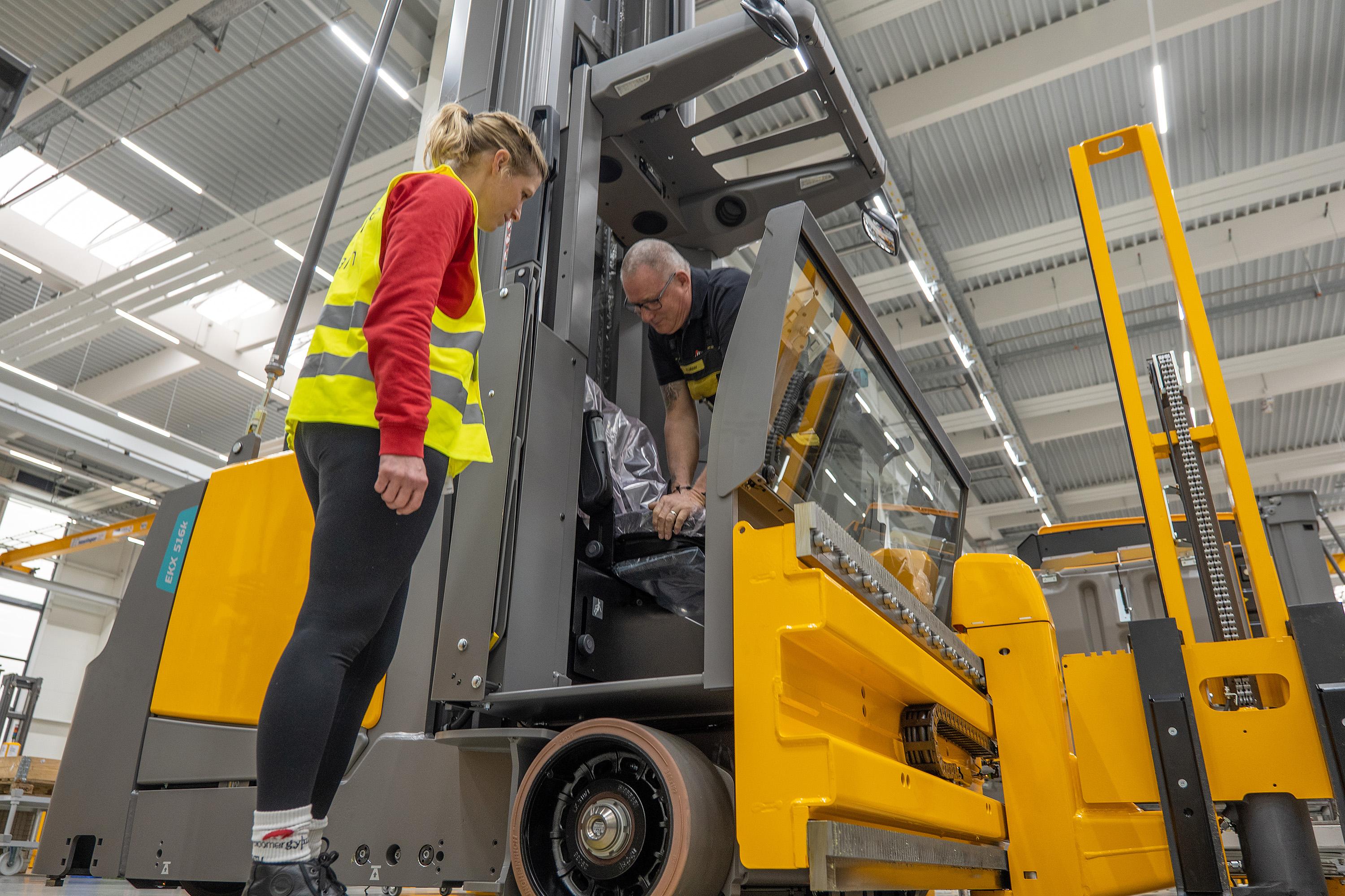 Ergonomie-Coach Monika Frötschl und Heinrich Lehner stehen an einem Gapelstapler, an dem er gerade einen Sitz montiert.