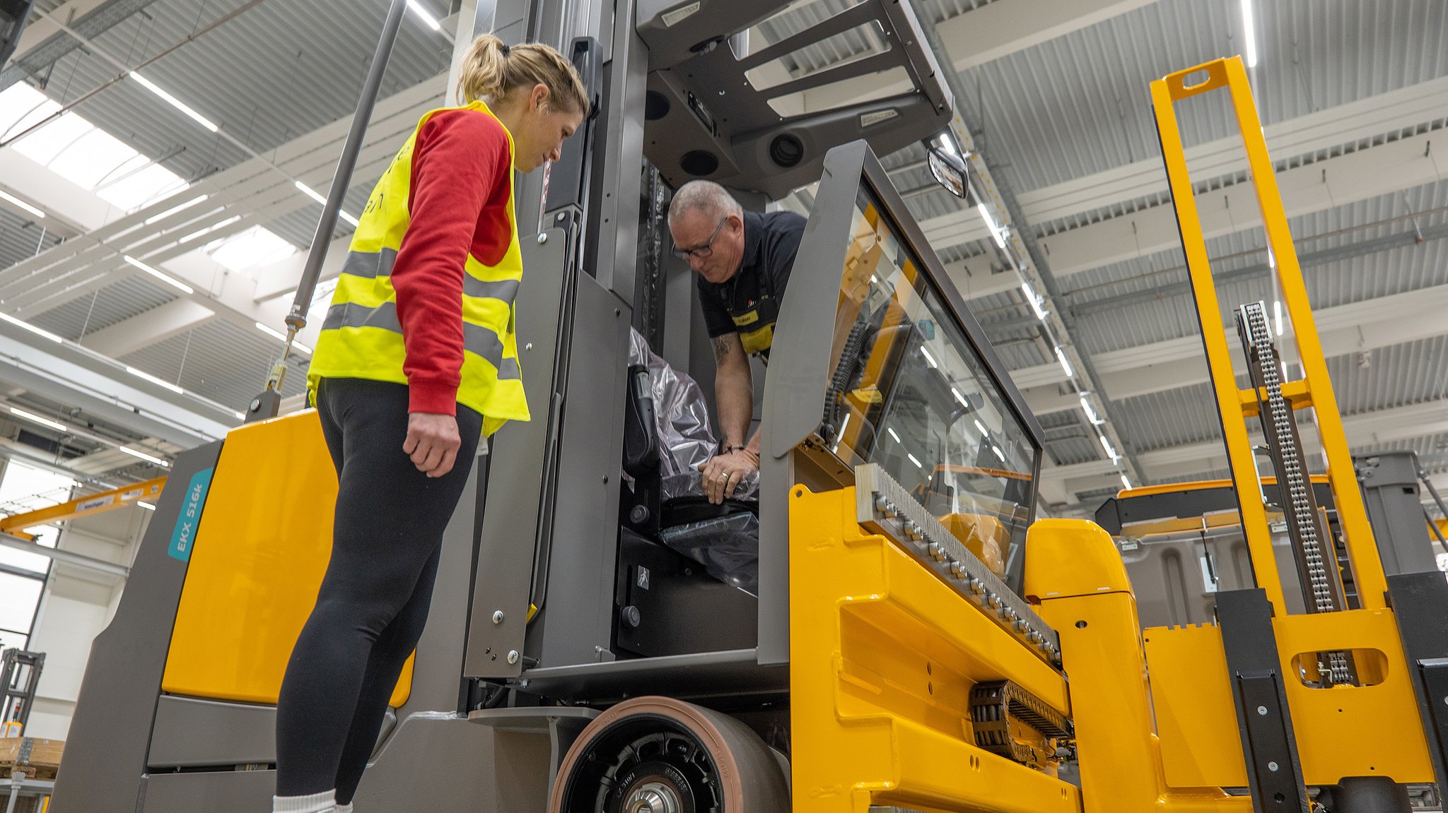 Ergonomie-Coach Monika Frötschl und Heinrich Lehner stehen an einem Gapelstapler, an dem er gerade einen Sitz montiert.