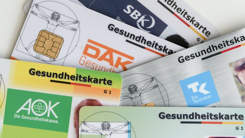 Gesundheitskarten verschiedener Krankenkassen liegen auf einem Tisch. | Bild: dpa-Bildfunk/Jens Kalaene Gesundheitskarten verschiedener Krankenkassen liegen auf einem Tisch.