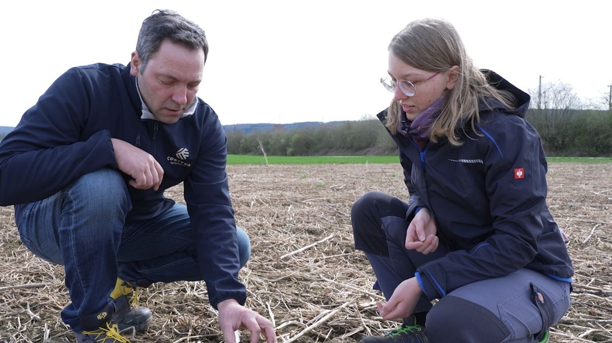 Landwirt Martin Goppelt und Franziska Sippl untersuchen einen Acker.