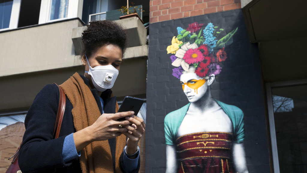 Woman using her smartphone while wearing a face mask