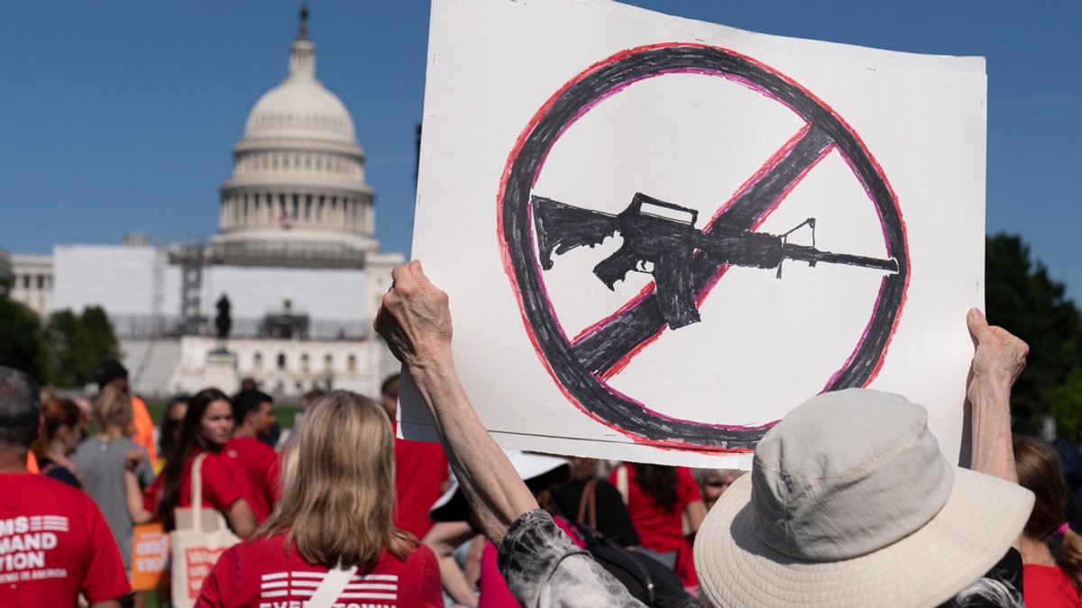 Eine Frau hält während einer Veranstaltung nahe des Kapitols ein Schild zum Thema Waffenverbot hoch.
