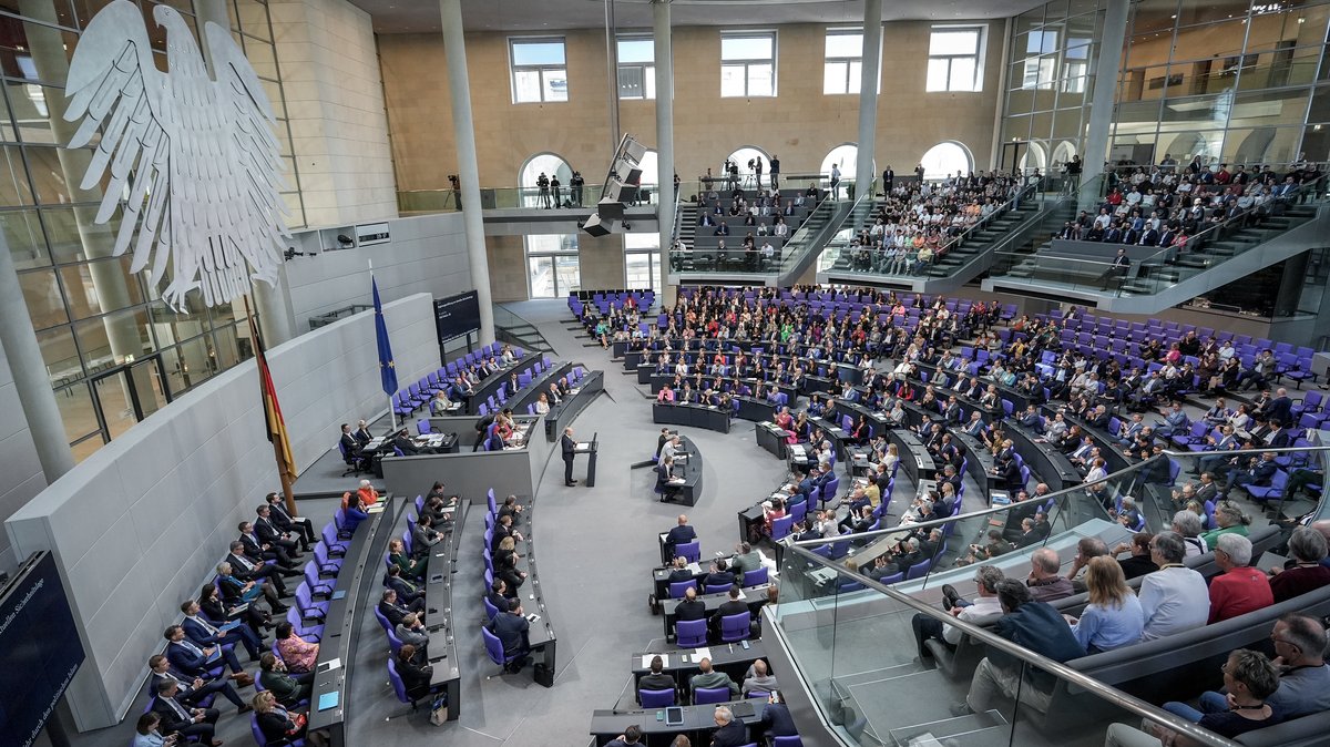 Blick aus den oberen Rängen hinunter ins fast vollbesetzte Plenum des Bundestags. Ein Mann steht am Rednerpult.