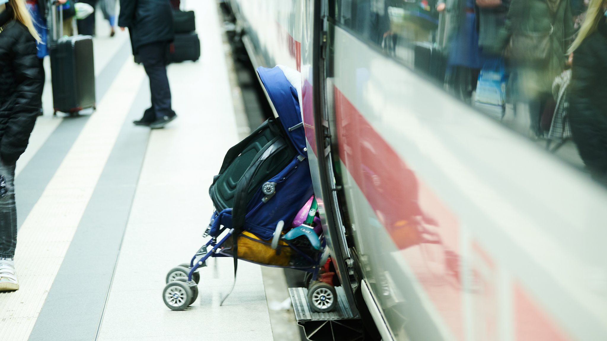 Ein Kinderwagen wird in den ICE gezogen.